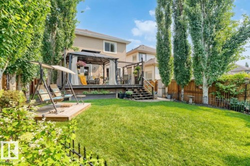 Expansive green lawn with mature trees, a multi-level deck featuring a gazebo, and a raised wood-finish patio - 22 Voleta Crest, Spruce Grove, AB 