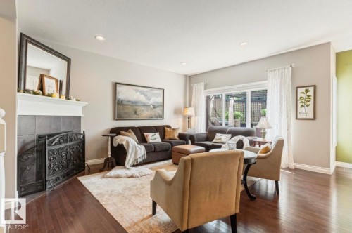 Hardwood-finish flooring, recessed lighting, tile fireplace surround, white mantel, and large picture windows - 22 Voleta Crest, Spruce Grove, AB 