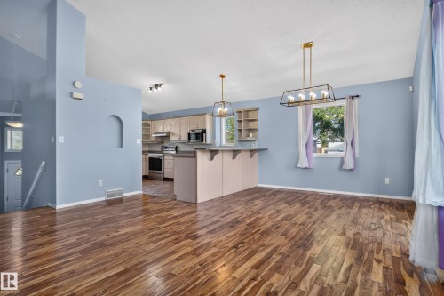 Wood-finish flooring throughout, with a kitchen featuring light cabinetry and stainless steel appliances - 13803 130A Avenue Nw, Edmonton, AB 