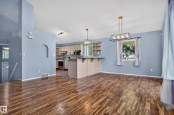 Wood-finish flooring throughout, with a kitchen featuring light cabinetry and stainless steel appliances - 