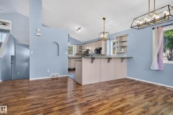 Vaulted ceilings with recessed lighting, wood-finish flooring, kitchen island with integrated shelving, and bronze-finish light fixtures - 