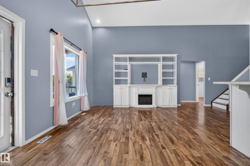 Wood-finish flooring, vaulted ceiling, built-in entertainment center, electric fireplace, and a large window - 13803 130A Avenue Nw, Edmonton, AB 