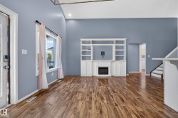 Wood-finish flooring, vaulted ceiling, built-in entertainment center, electric fireplace, and a large window - 