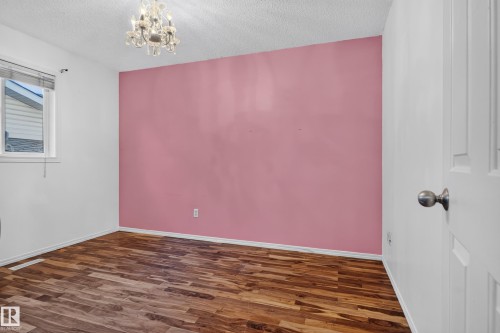 Wood-finish flooring, white trim, a crystal chandelier, and a window with blinds - 13803 130A Avenue Nw, Edmonton, AB 