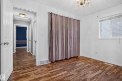 Wood-finish flooring throughout, bright window with blinds, and an overhead chandelier light fixture - 