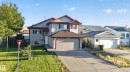 Two-story residence featuring light gray siding with dark trim accents, an attached garage, a paved driveway, and a front yard with manicured lawn - 13803 130A Avenue Nw, Edmonton, AB 