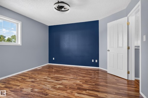 Wood-finish flooring, accent wall, white trim, window, and ceiling light fixture - 13803 130A Avenue Nw, Edmonton, AB 