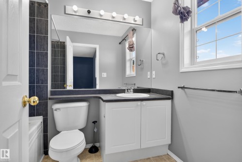 White vanity with cabinet storage, dark countertop, and integrated sink - 13803 130A Avenue Nw, Edmonton, AB 
