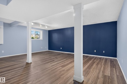 Spacious room featuring wood-finish flooring, light blue and dark blue painted walls, and track lighting - 13803 130A Avenue Nw, Edmonton, AB 