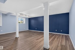 Spacious room featuring wood-finish flooring, light blue and dark blue painted walls, and track lighting - 