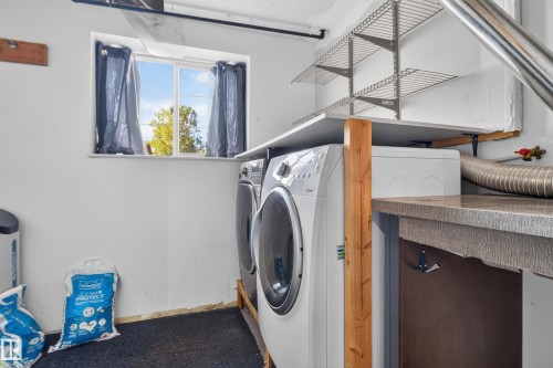 Utility space featuring a window, built-in countertop, shelving, and installed laundry appliances - 13803 130A Avenue Nw, Edmonton, AB 