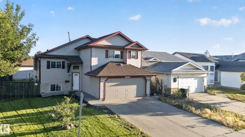 Two-story residence featuring light-colored siding, a two-car garage, and a sloped driveway - 13803 130A Avenue Nw, Edmonton, AB 