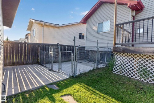 Fenced-in concrete patio with chain-link gates, wood fencing, and a grassy area - 13803 130A Avenue Nw, Edmonton, AB 