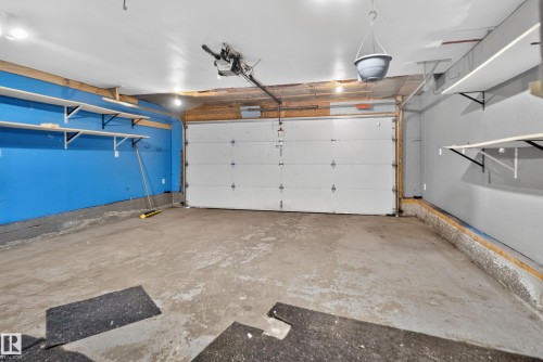 Garage with concrete flooring, overhead lighting, and built-in shelving - 13803 130A Avenue Nw, Edmonton, AB 