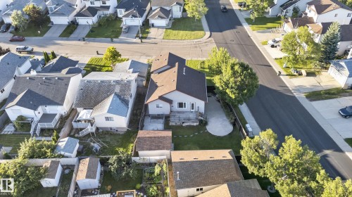 Aerial perspective of a residential property featuring a brown shingle roof, a rear deck, and a concrete patio - 13803 130A Avenue Nw, Edmonton, AB 