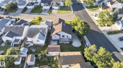 Aerial perspective of a residential property featuring a brown shingle roof, a rear deck, and a concrete patio - 