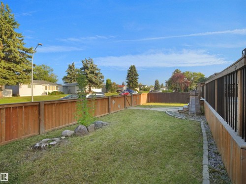 Expansive backyard featuring a manicured lawn, wood fencing, and a built-in deck with railings - 13338 131 Street Nw, Edmonton, AB 