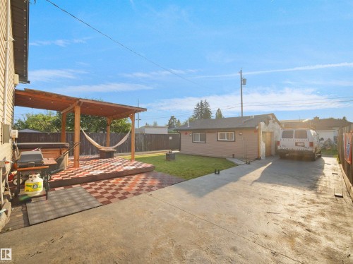 Wood pergola over a patterned patio, expansive concrete driveway, and a detached structure with a pitched roof - 13338 131 Street Nw, Edmonton, AB 