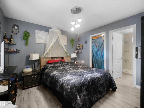 Recessed wood-finish headboard, light wood-finish flooring, contemporary ceiling light fixture, and white interior door - 13338 131 Street Nw, Edmonton, AB 