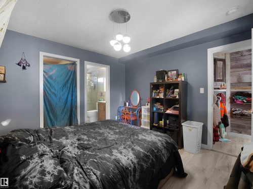 Modern multi-bulb pendant light fixture, wood-finish flooring, and two distinct doorways - 13338 131 Street Nw, Edmonton, AB 