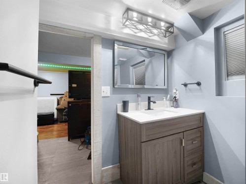 Powder room featuring a wood-finish vanity with countertop sink, matte black faucet, and framed mirror - 13338 131 Street Nw, Edmonton, AB 
