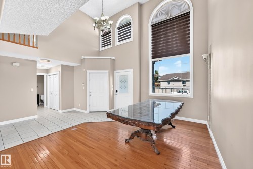 Vaulted ceiling with an ornate chandelier, multiple arched transom windows, wood-finish flooring, and white tile flooring - 4711 152 Avenue Nw, Edmonton, AB 