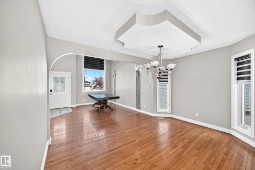 Spacious open-concept room with warm wood-finish flooring, soaring vaulted ceiling with recessed lighting, and abundant natural light from multiple windows - 4711 152 Avenue Nw, Edmonton, AB 