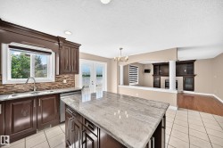 Gourmet kitchen featuring dark wood cabinetry, stone-finish countertops, and a large center island with seating - 
