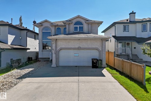 Stucco exterior with an attached garage, arched windows, and a concrete driveway - 4711 152 Avenue Nw, Edmonton, AB 