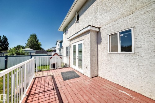 Exterior deck with wood-finish surface, white railing, and dual-pane glass doors - 4711 152 Avenue Nw, Edmonton, AB 