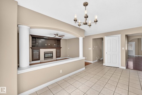 Tile flooring, arched entryway, built-in media cabinetry, fireplace, and ceiling fan - 4711 152 Avenue Nw, Edmonton, AB 