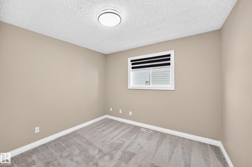 Neutral-toned walls, grey carpeting, and a window with blinds - 4711 152 Avenue Nw, Edmonton, AB 