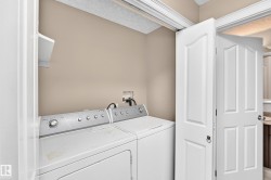 Laundry area with built-in shelving, bifold doors, and a neutral wall finish - 