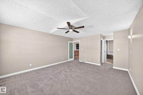 Spacious room featuring vaulted ceilings, a ceiling fan, neutral wall tones, and gray carpeting - 4711 152 Avenue Nw, Edmonton, AB 