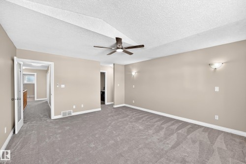 Spacious room with sloped ceiling, ceiling fan, neutral wall paint, and wall-mounted light fixtures - 4711 152 Avenue Nw, Edmonton, AB 
