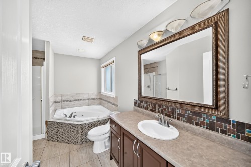 Spacious bathroom featuring a corner jetted tub, a separate shower, and a vanity with an integrated sink - 4711 152 Avenue Nw, Edmonton, AB 
