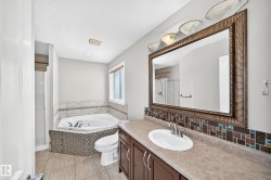 Spacious bathroom featuring a corner jetted tub, a separate shower, and a vanity with an integrated sink - 