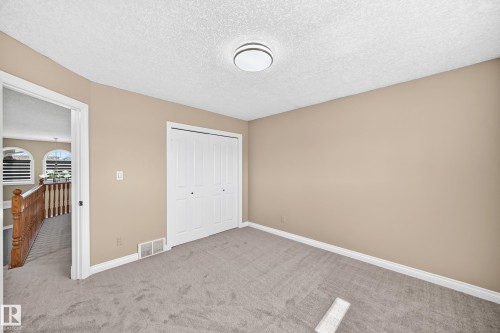 Wall-to-wall carpeting, neutral wall color, and a built-in closet with bifold doors - 4711 152 Avenue Nw, Edmonton, AB 