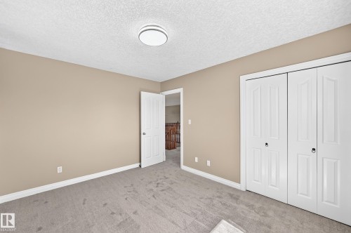 Neutral-toned walls, textured ceiling, flush-mount ceiling light, white trim, and gray carpeting - 4711 152 Avenue Nw, Edmonton, AB 
