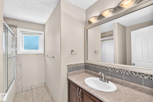Vanity with integrated sink, mosaic tile backsplash, and mounted mirror - 4711 152 Avenue Nw, Edmonton, AB 