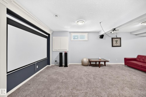 Projection screen, recessed lighting, wall-mounted storage cabinet, window with plantation shutters, and soft carpeting - 4711 152 Avenue Nw, Edmonton, AB 