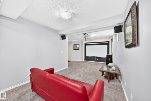 Carpeted room featuring a projector and a large screen - 4711 152 Avenue Nw, Edmonton, AB 