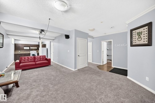 Spacious carpeted area with neutral wall tones and crown molding - 4711 152 Avenue Nw, Edmonton, AB 