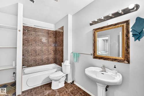 White pedestal sink with chrome faucet, a decorative framed mirror, and a five-light vanity fixture - 4711 152 Avenue Nw, Edmonton, AB 