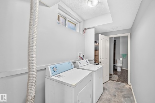 Laundry area with a window, overhead lighting, and an adjacent bathroom featuring a toilet and dark flooring - 4711 152 Avenue Nw, Edmonton, AB 