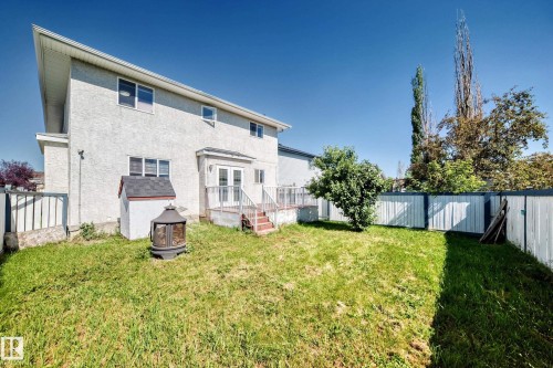 Expansive backyard featuring a manicured lawn, established trees, and a raised wooden deck with white railings - 4711 152 Avenue Nw, Edmonton, AB 
