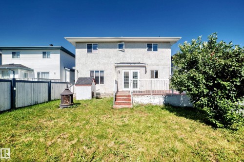 Rear exterior featuring a deck with white railings, double glass doors, and a stucco facade - 4711 152 Avenue Nw, Edmonton, AB 