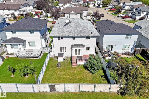 Expansive backyard featuring a manicured lawn, white privacy fencing, and a red-toned wood deck - 4711 152 Avenue Nw, Edmonton, AB 