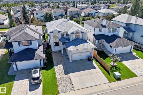 Front-facing entry, attached two-car garage, concrete driveway, and manicured front lawn - 4711 152 Avenue Nw, Edmonton, AB 