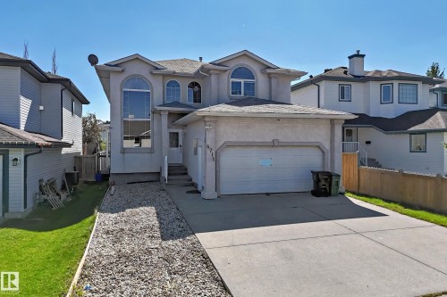 Stucco exterior with arched windows, an attached front-entry garage, paved driveway, and a gravel pathway - 4711 152 Avenue Nw, Edmonton, AB 